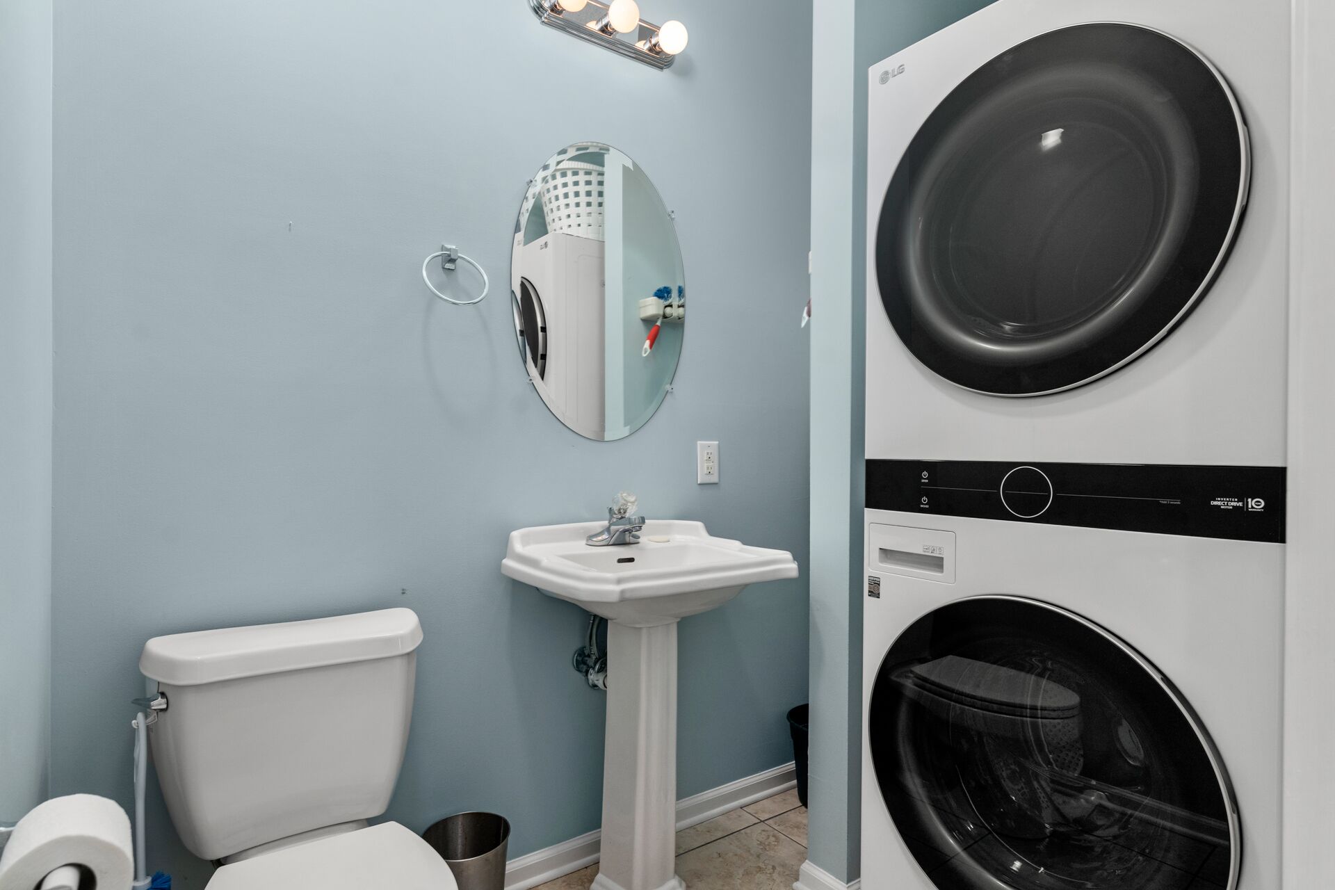 Een kleine badkamer met toilet, wastafel en twee gestapelde wasmachines.
