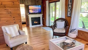 A cozy living room with a fireplace, a television, and a view of the outdoors.