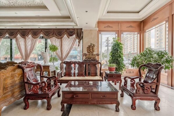 A spacious room with a large window, a sofa set, a coffee table, and potted plants. - Hong Qiao Prince Hotel (Dingbian)