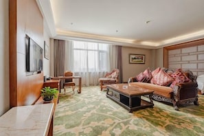 Ein Wohnzimmer mit einer Couch, einem Couchtisch, einem Fernseher und einer Pflanze.