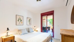 A bedroom with a bed, two bedside tables, a nightstand, and a wooden dresser.