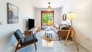 A modern living room with a sofa, armchair, TV, and lamp.