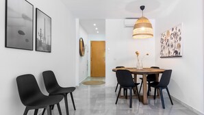 A dining area with a wooden table and black chairs, a hanging pendant light, and framed artwork on the walls.