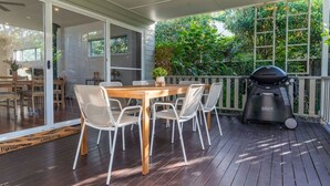 Eine Terrassengaststätte mit Holztisch und -stühlen, einem Grill und Blick ins Grüne.