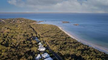 Vista aérea de una zona costera con una carretera que conduce a una hilera de casas a lo largo de la playa.