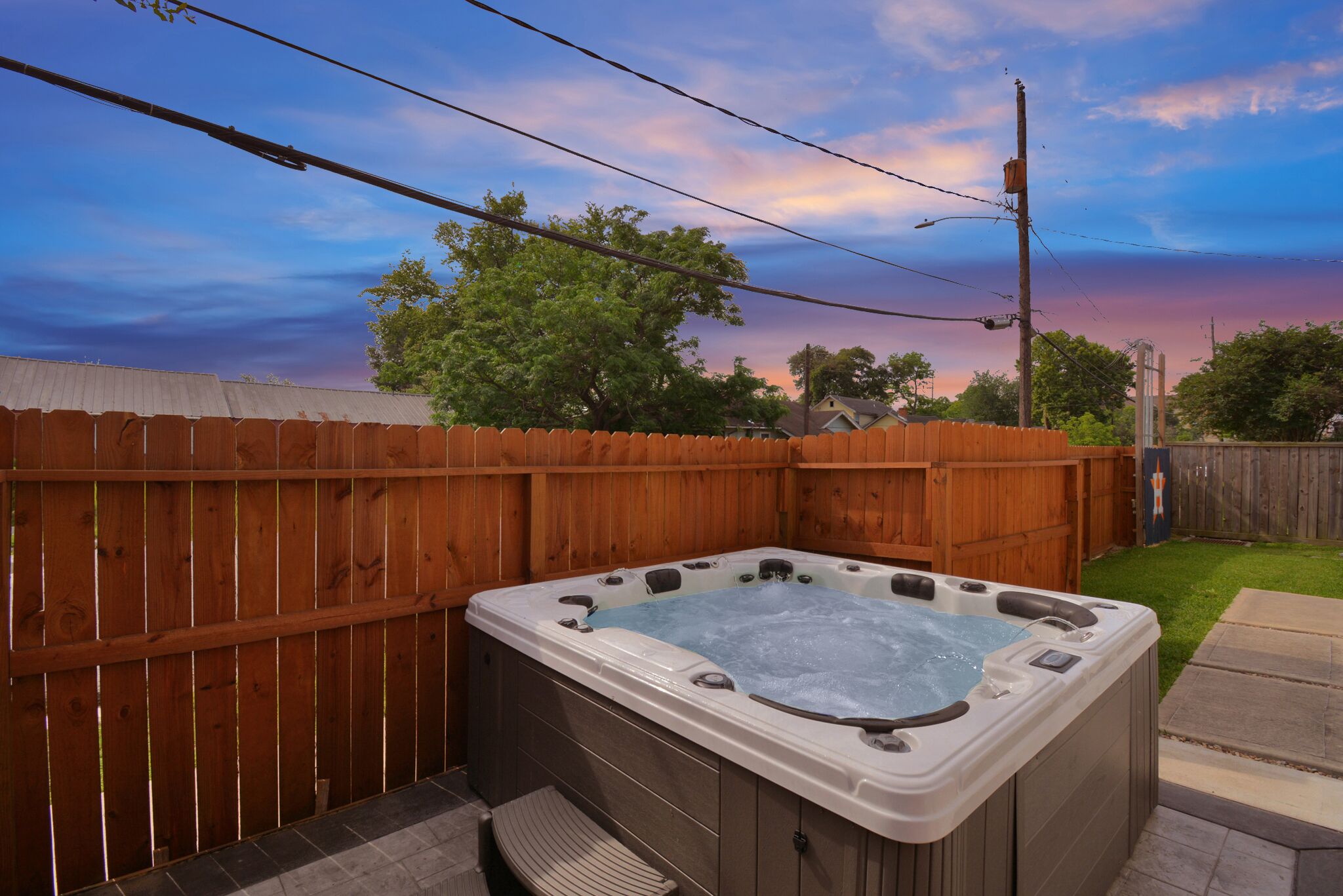 Ein Whirlpool in einem Garten mit Holzzaun und Blick zum Himmel.