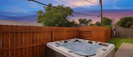 Ein Whirlpool in einem Garten mit Holzzaun und Blick zum Himmel.