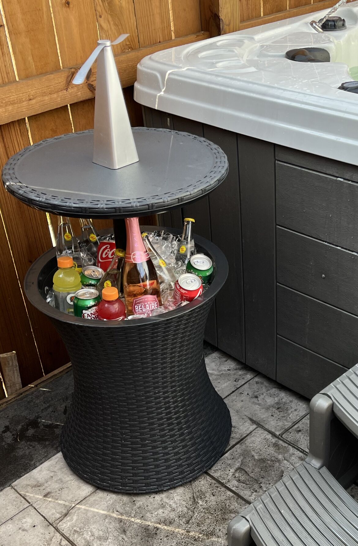 A hot tub with a black wicker table in front, holding various bottles and cans.