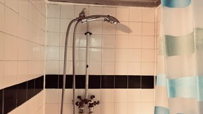 A shower with a chrome faucet and a flexible hose.