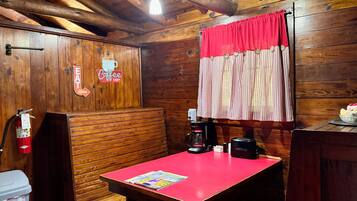 Interior em madeira com uma mesa vermelha, uma máquina de café e um extintor de incêndio.