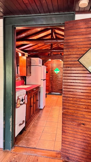 A kitchen with wooden cabinets, a refrigerator, and a stove.