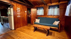 A wooden interior with a sofa, a table, and a kitchen area.