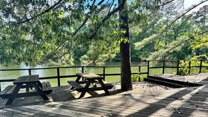 Un muelle de madera con mesas de picnic dando a un cuerpo de agua.
