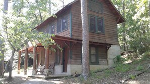 Eine Holzhütte mit Veranda, zwei Fenstern und einem Steinfundament.
