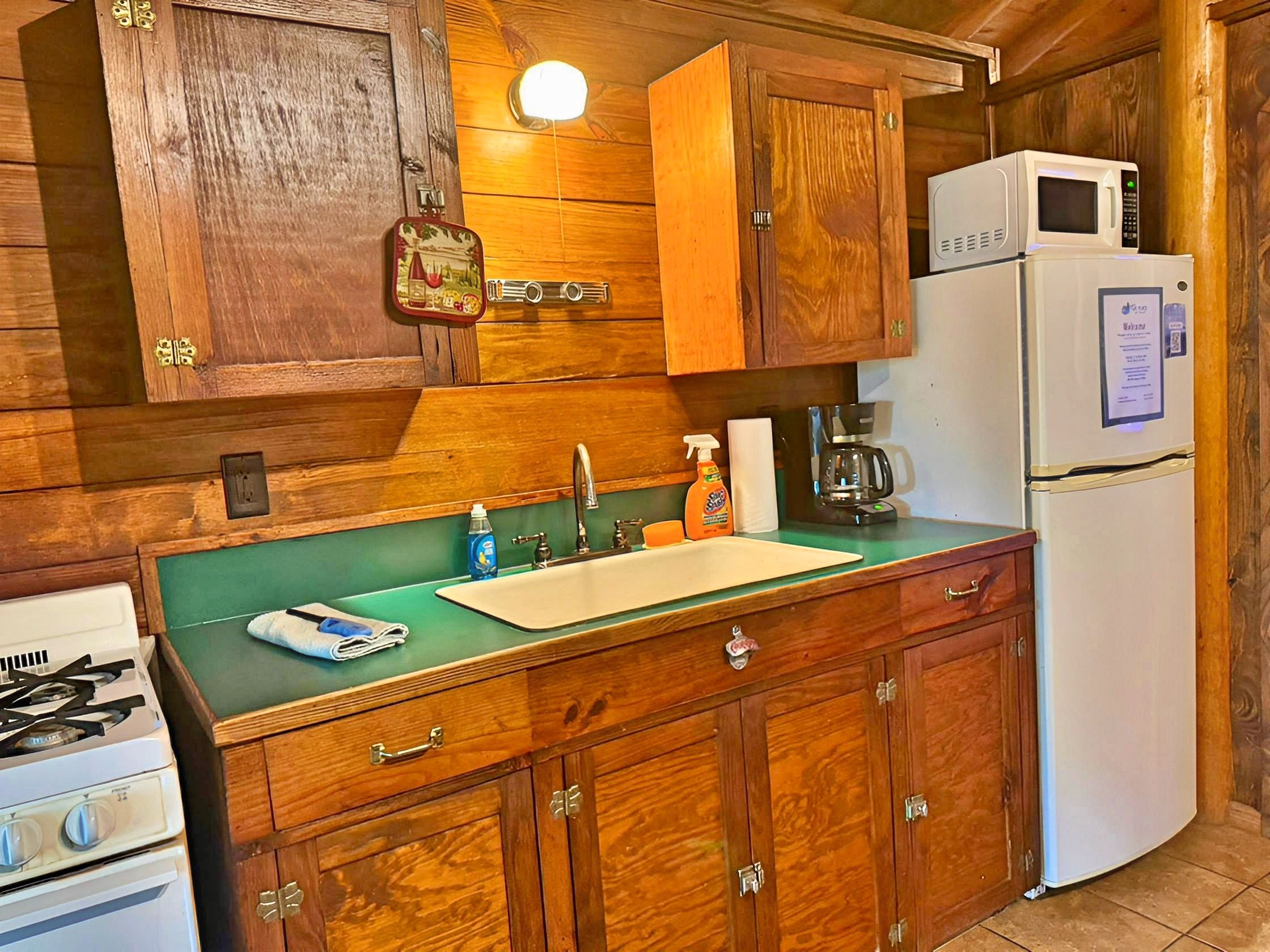 A kitchen with wooden cabinets, a sink, a stove, and a refrigerator.