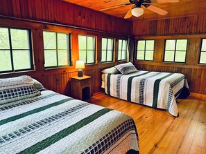 A cabin with two beds, a wooden ceiling, and large windows. - A-ARKANSAS ROCKHOUND - Vintage Style, Lake View, Swimming, Fishing, Docks, Pet Friendly! (Hot Springs National Park)