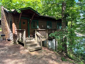 A rustic cabin with a stone wall, wooden steps, and a green door. - A-ARKANSAS ROCKHOUND - Vintage Style, Lake View, Swimming, Fishing, Docks, Pet Friendly! (Hot Springs National Park)