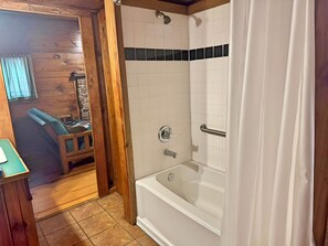 Une salle de bain avec une baignoire, une douche, des murs en bois et un petit coin salon.