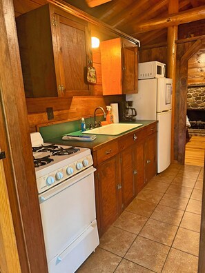 Une cuisine avec des meubles de rangement en bois, une cuisinière à gaz, un évier et un réfrigérateur.