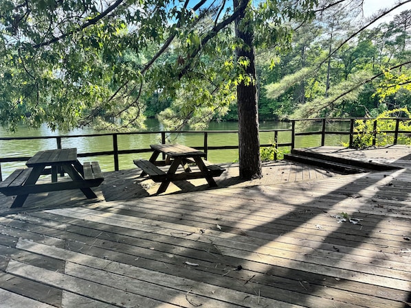 Un muelle de madera con mesas de picnic dando a un cuerpo de agua.