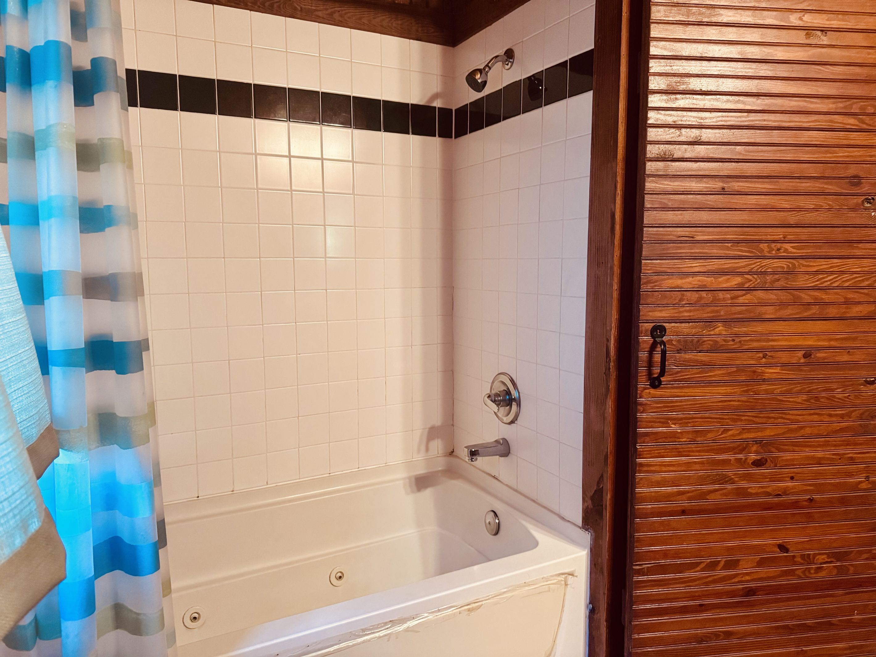 A bathroom with a bathtub, a shower, and a wooden door.