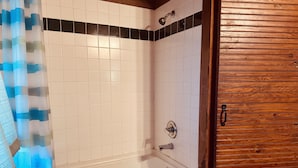 Ein Badezimmer mit einer Badewanne, einer Dusche und einer Holztür.