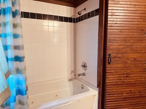 A bathroom with a bathtub, a shower, and a wooden door.