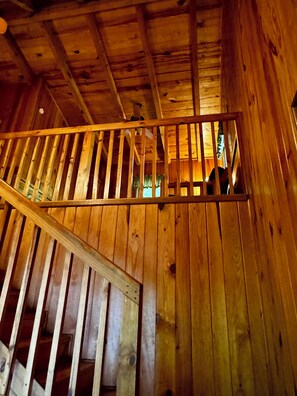 Un interior de madera con una escalera que sube a un nivel superior.