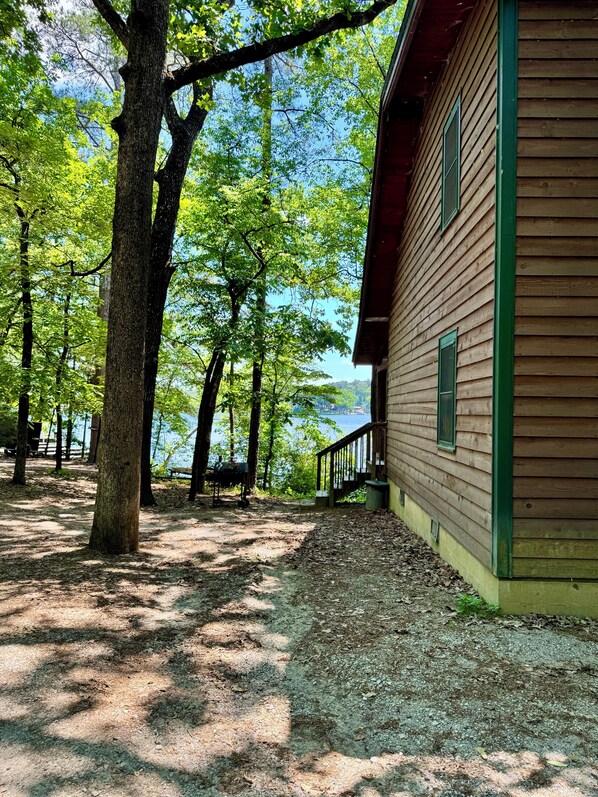 Une cabane en bois dotée d’une terrasse, entourée d’arbres et offrant une vue sur le lac.
