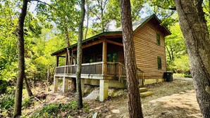 Eine Holzhütte mit Veranda, umgeben von Bäumen.
