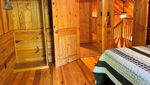 Ein Holzinnenraum mit einem Bett, einer Tür und einer Treppe.