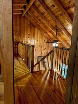 Un intérieur en bois avec un escalier, des murs en bois et un ventilateur de plafond.