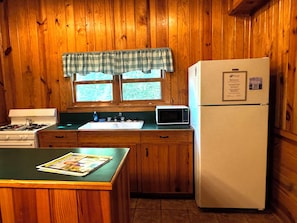 Une cuisine avec des meubles de rangement en bois, une cuisinière, un four à micro-ondes et un réfrigérateur.