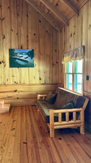 Un intérieur en bois avec un banc en bois, une fenêtre avec des rideaux et un tableau encadré au mur.