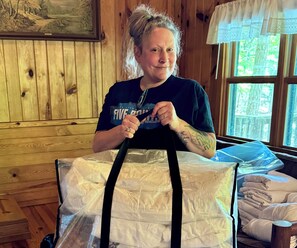 Une personne tenant un grand cadeau emballé dans une pièce aux murs en bois et dotée d’une fenêtre.