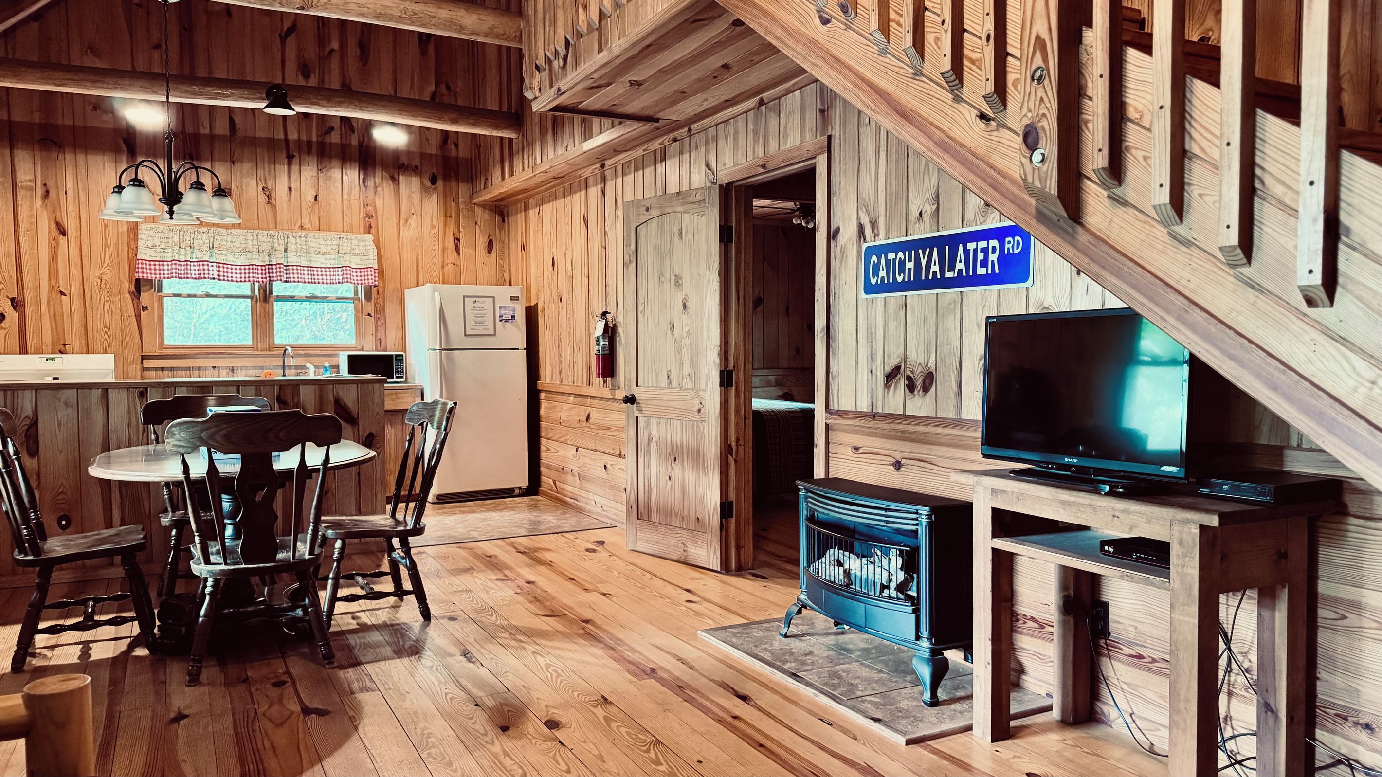 A wooden interior with a kitchen, dining area, and a television on a wooden stand.