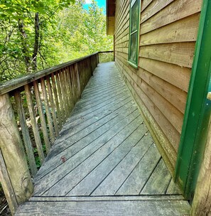 A wooden deck with a railing, leading to a building with green trim. - Cabin F-Lakeside-Swim-Fish-Docks-Pet Friendly (Hot Springs National Park)