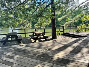 A wooden deck with picnic tables overlooking a body of water, surrounded by trees. - F-CATCH YA LATER! Vintage Style Lakefront Cabin-Swim-Fish-Docks-Pet Friendly! (Hot Springs National Park)