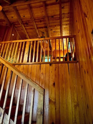 Interior de madera con una escalera y vistas a una habitación con ventana.