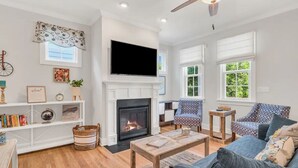 Una sala de estar con chimenea, televisor y muebles con estampado.