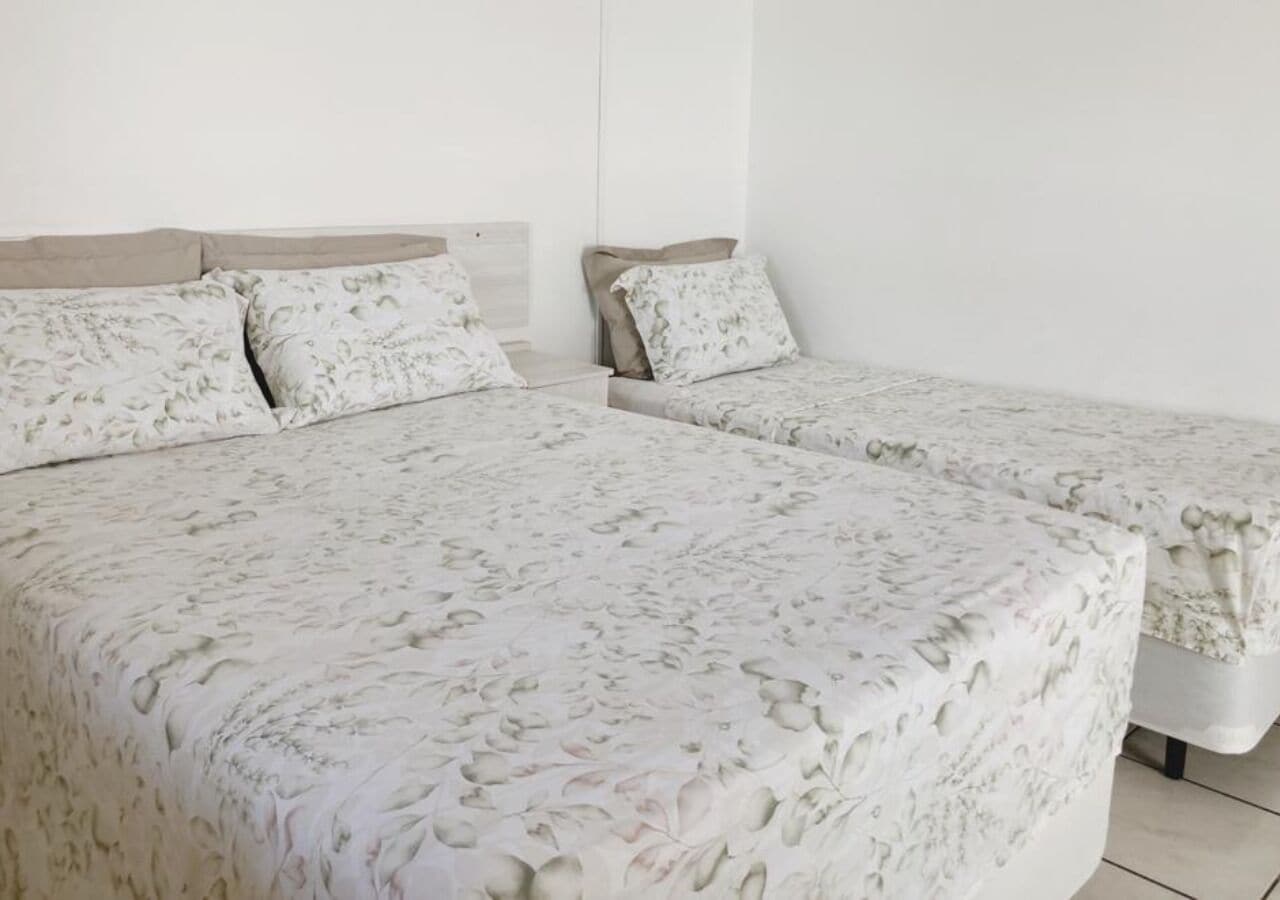 Een slaapkamer met twee bedden, elk met een bloemenprint beddeken en passende kussens.