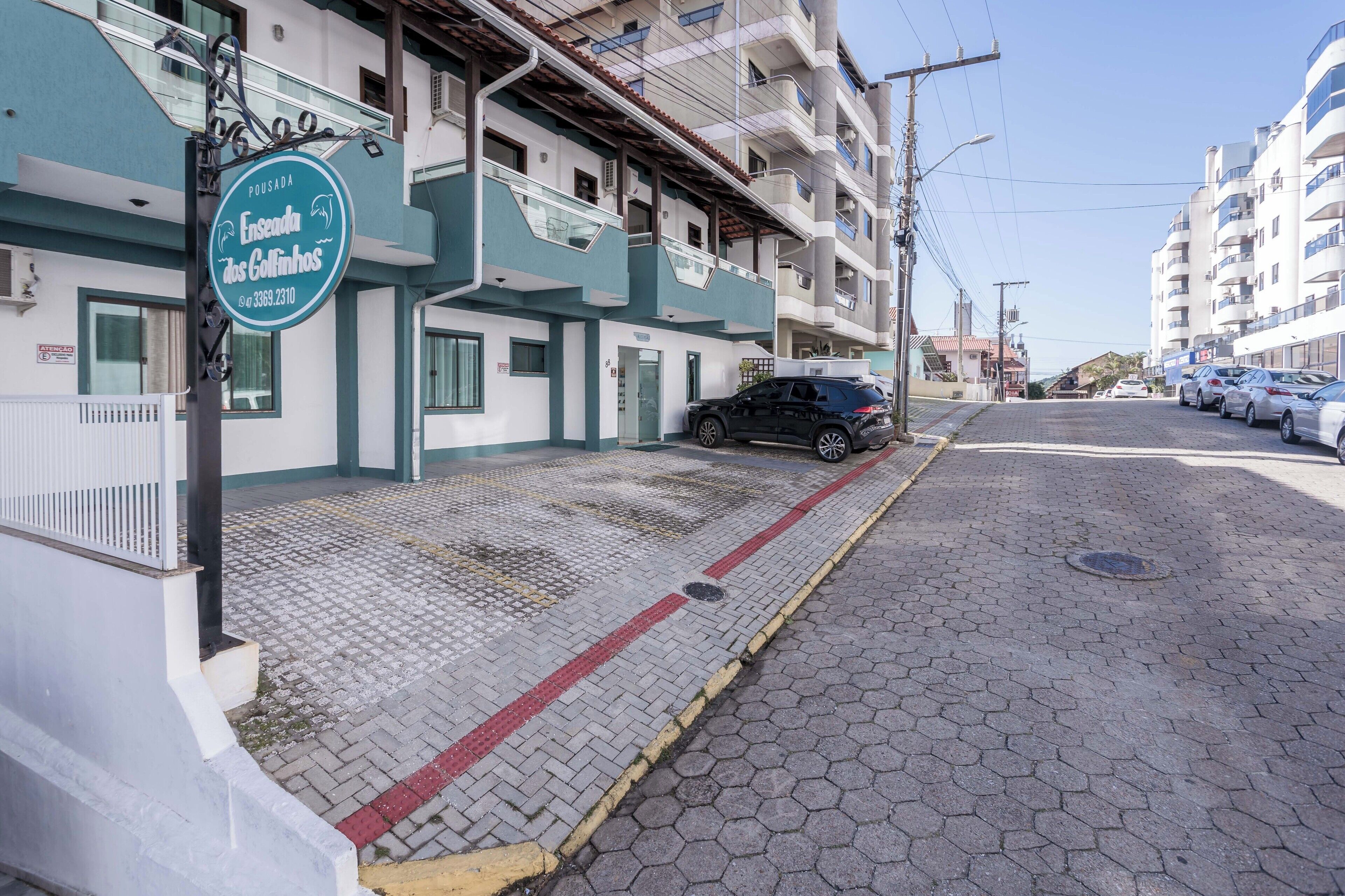 Un edificio con un cartello che indica 'Ensenada dos Calvões' e un marciapiede lastricato con cordolo.