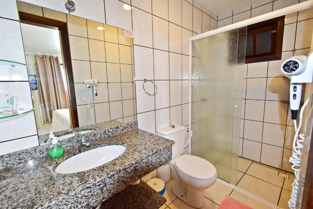 Un bagno con lavabo su piano in granito, un WC e cabina doccia in vetro.