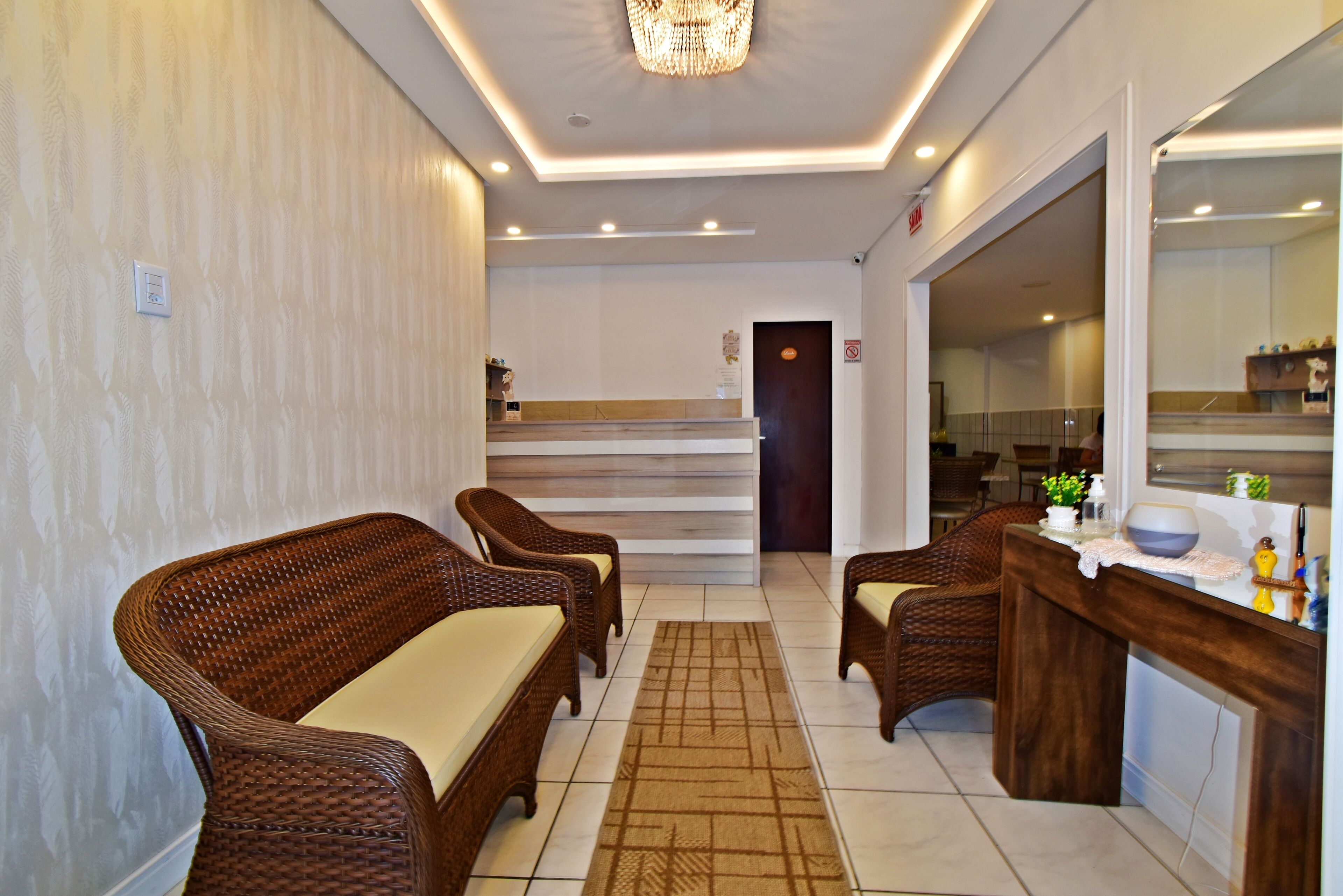 A reception area with wicker furniture, a reception desk, and a mirror.