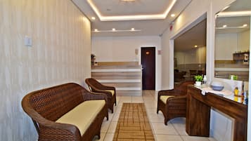 A reception area with wicker furniture, a reception desk, and a mirror.