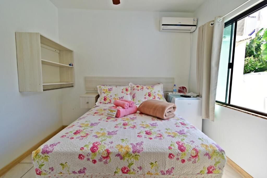Un dormitorio con cama, mesita de noche, estante y equipo de aire acondicionado.