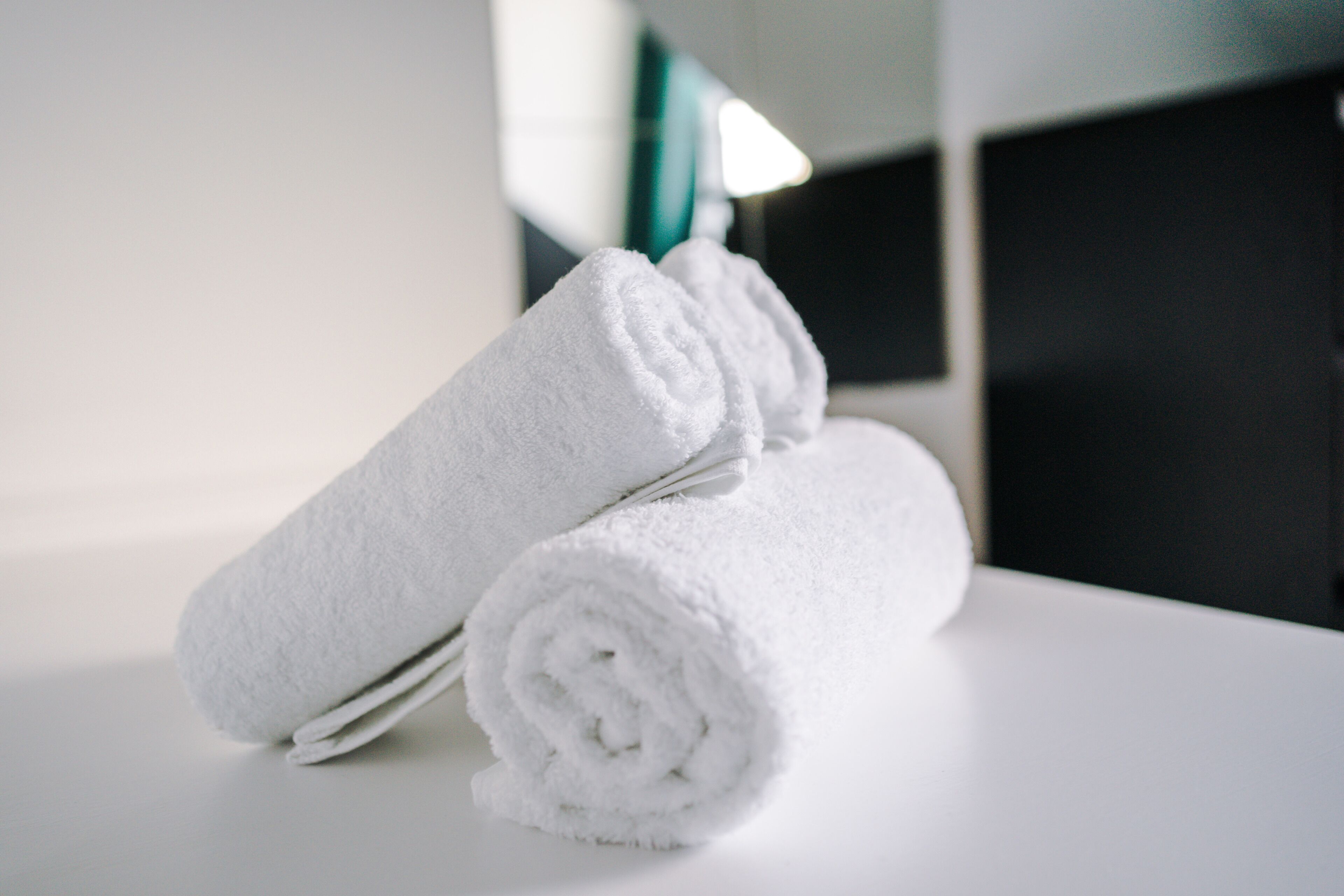 A stack of white towels on a white surface in a room with a modern design.