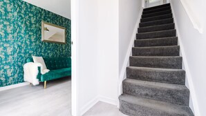 Een trap met een donker tapijt dat leidt naar een kamer met een groene bank en een witte vacht.