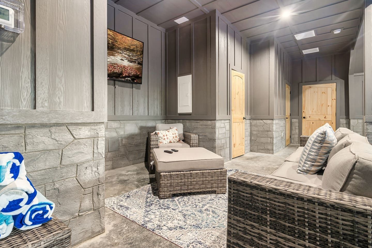 A spa area with a stone wall, a wicker sofa, a cushioned bench, and a painting on the wall.