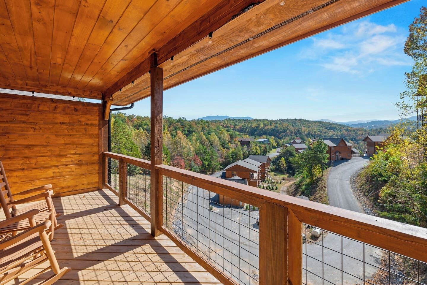 Un balcon en bois offrant une vue sur une route sinueuse et des maisons situées dans une région vallonnée.